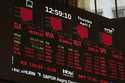A screen displays financial news as traders work on the floor at the New York Stock Exchange in New…