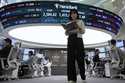 A currency trader passes by a screen showing the Korea Composite Stock Price Index…